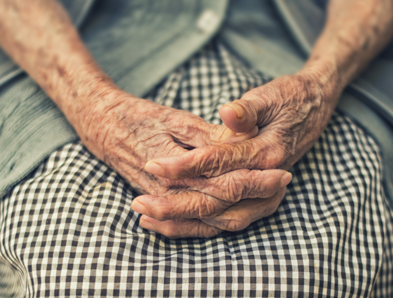 Primer plano de manos con dedos entrelazados de mujer de la tercera edad