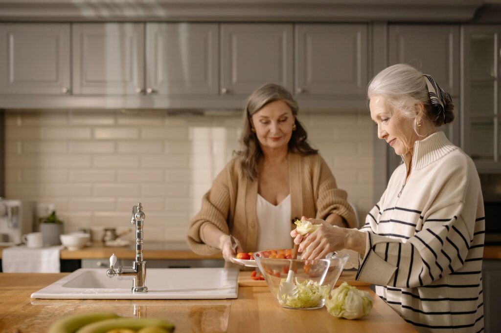 Dos mujeres mayores preparando una ensalada juntas en la cocina